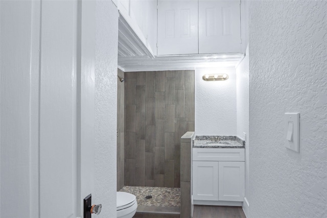 bathroom featuring vanity, toilet, and tiled shower