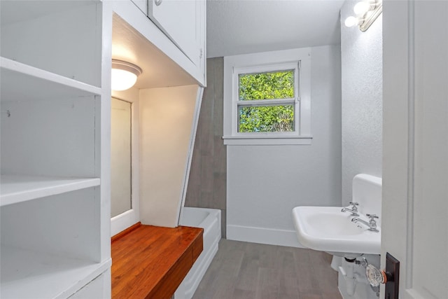 bathroom featuring hardwood / wood-style flooring, a washtub, and sink