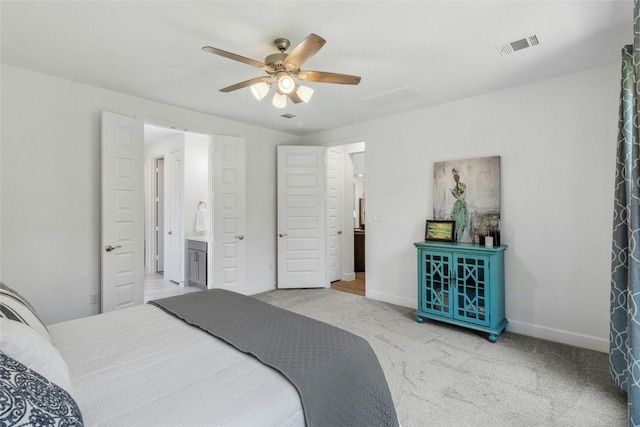 bedroom featuring light colored carpet, ceiling fan, and ensuite bathroom