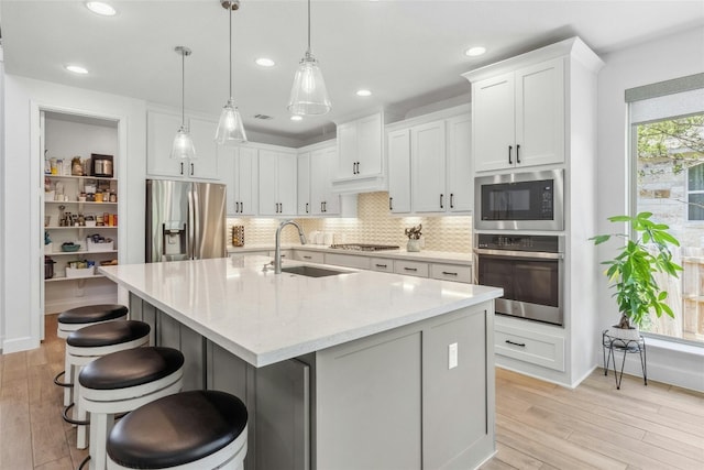 kitchen featuring appliances with stainless steel finishes, decorative light fixtures, white cabinetry, and sink