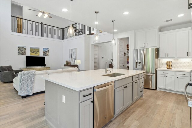 kitchen with appliances with stainless steel finishes, a center island with sink, white cabinetry, and sink