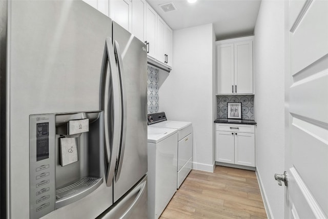 laundry room with cabinets, washing machine and dryer, and light hardwood / wood-style flooring