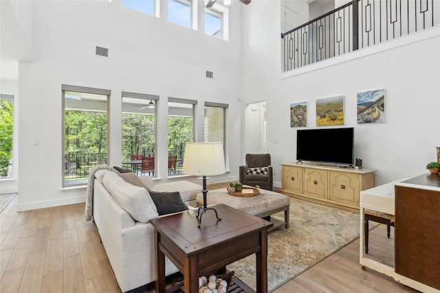 living room with ceiling fan, a healthy amount of sunlight, and a towering ceiling