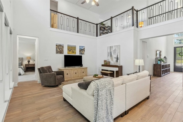 living room featuring ceiling fan, a high ceiling, and hardwood / wood-style flooring