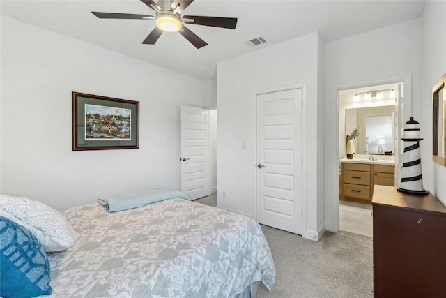 bedroom featuring light colored carpet, ensuite bath, and ceiling fan