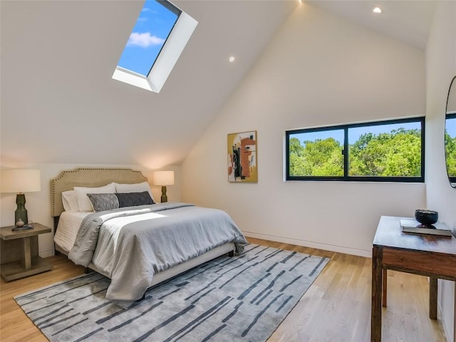 bedroom featuring light wood-type flooring, high vaulted ceiling, and a skylight