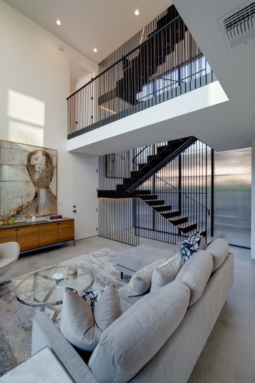 living room with a towering ceiling and concrete floors