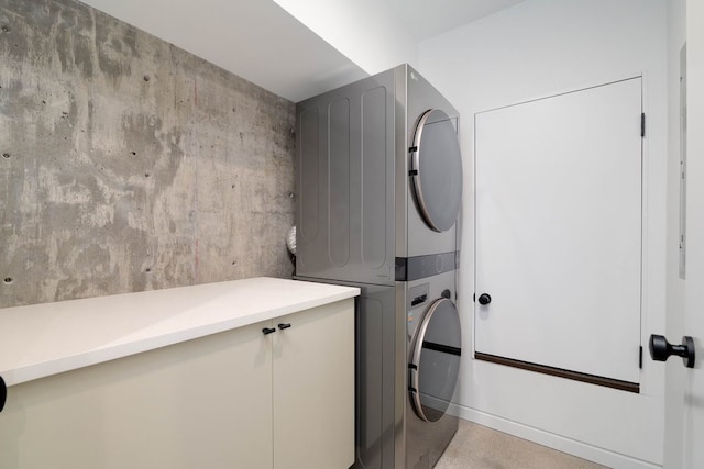 laundry room with stacked washer / drying machine and cabinets