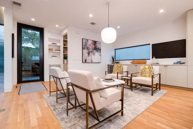 living room featuring built in features, expansive windows, and light hardwood / wood-style floors