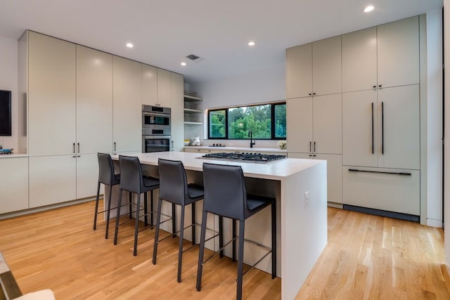 kitchen featuring a kitchen bar, a large island, light hardwood / wood-style floors, and appliances with stainless steel finishes