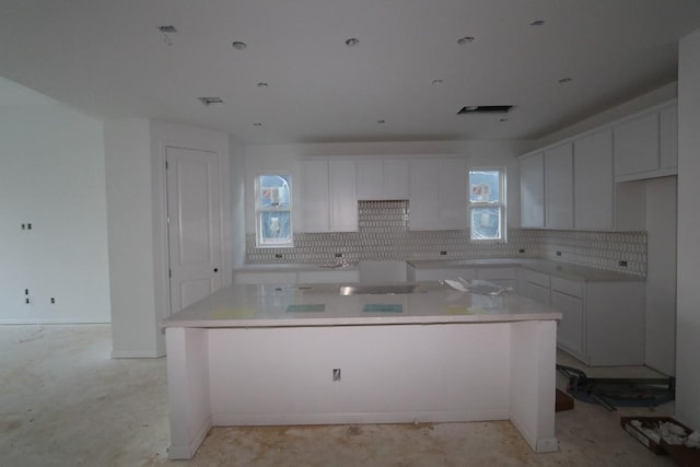 kitchen featuring stovetop, a center island, white cabinetry, and tasteful backsplash