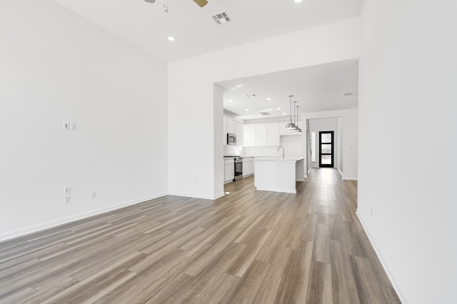 unfurnished living room featuring baseboards, visible vents, a ceiling fan, and light wood-style floors