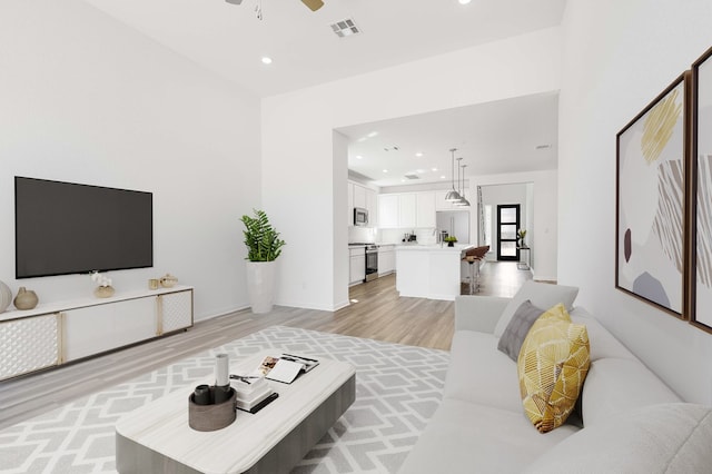 living room featuring light wood-style flooring, recessed lighting, visible vents, and ceiling fan