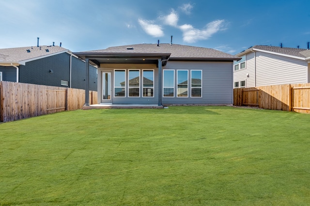 back of house featuring a yard, roof with shingles, a fenced backyard, and a patio area