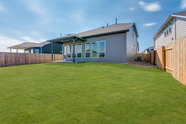 back of house with a fenced backyard, a patio area, central AC, and a yard