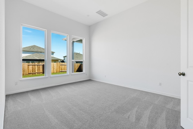 carpeted spare room featuring visible vents and baseboards