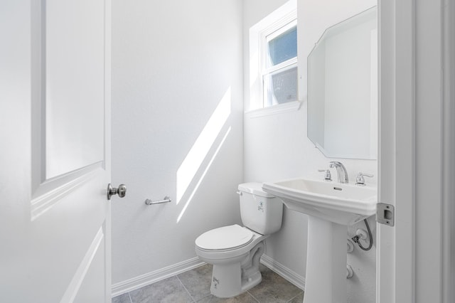 bathroom with tile patterned floors, baseboards, toilet, and a sink