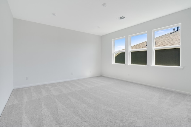 empty room with visible vents, light colored carpet, and baseboards