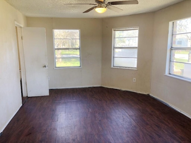 spare room with a wealth of natural light, ceiling fan, dark hardwood / wood-style floors, and a textured ceiling