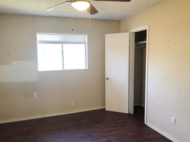 unfurnished bedroom with ceiling fan, dark hardwood / wood-style flooring, a textured ceiling, and a closet