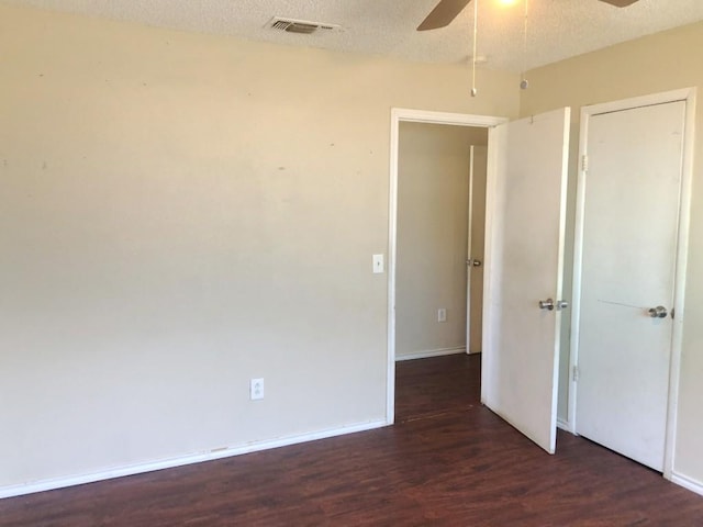 spare room featuring a textured ceiling, ceiling fan, and dark wood-type flooring