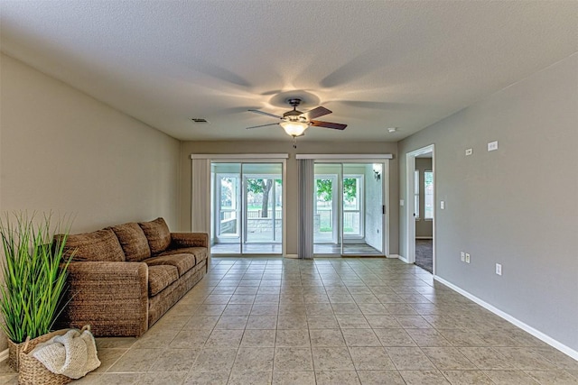 living room featuring ceiling fan, light tile patterned flooring, and a textured ceiling