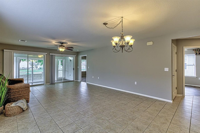 tiled spare room with a textured ceiling, ceiling fan with notable chandelier, and a healthy amount of sunlight