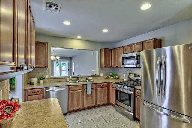 kitchen featuring decorative backsplash, stainless steel appliances, sink, an inviting chandelier, and light tile patterned flooring