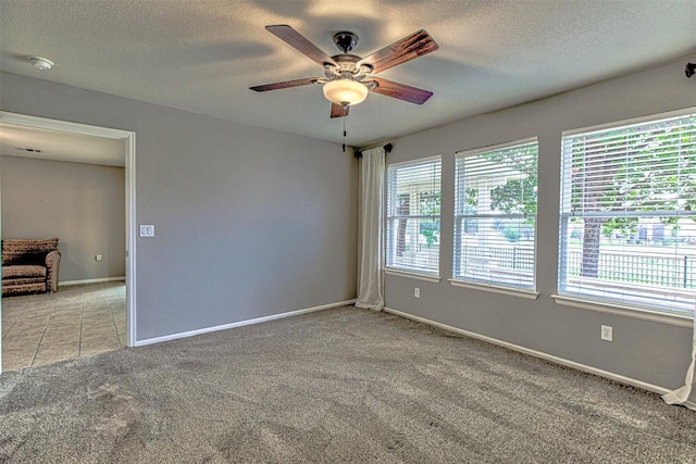 carpeted spare room with a wealth of natural light, ceiling fan, and a textured ceiling