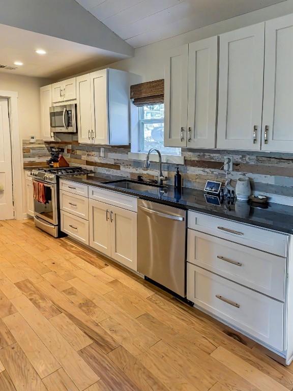 kitchen featuring tasteful backsplash, sink, white cabinets, and appliances with stainless steel finishes