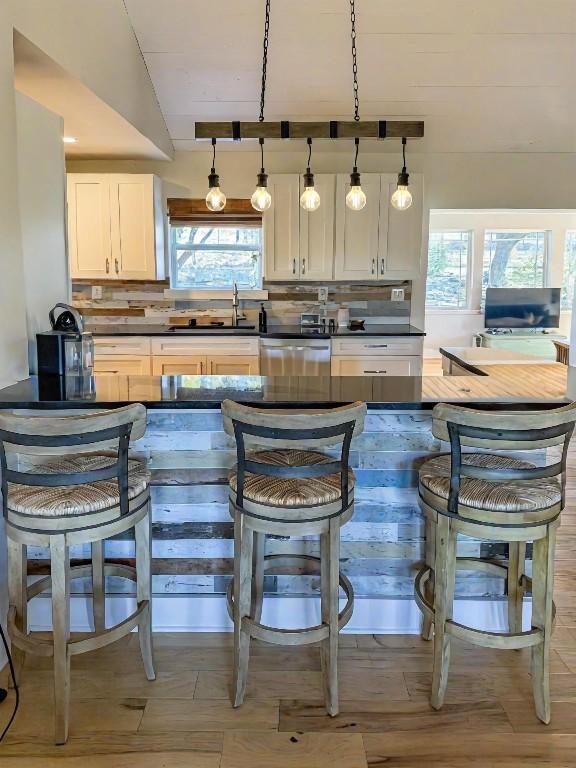 bar with dishwasher, sink, decorative light fixtures, and tasteful backsplash