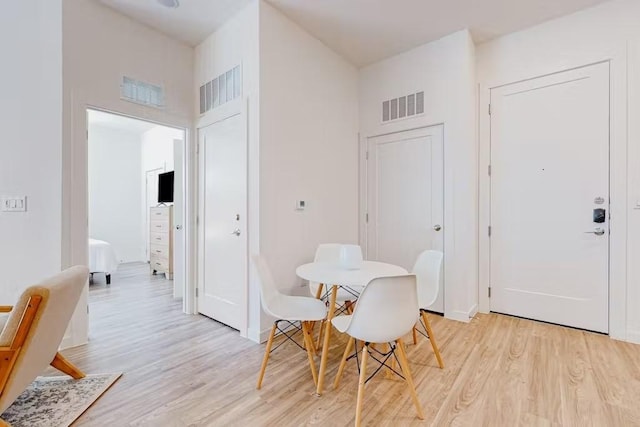 dining space with a towering ceiling and light hardwood / wood-style floors