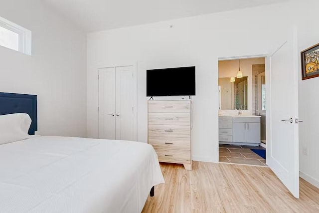 bedroom with a closet, light hardwood / wood-style flooring, and ensuite bath