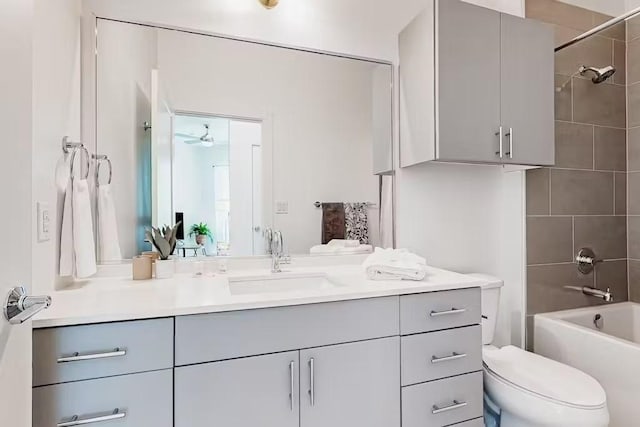 full bathroom featuring ceiling fan, vanity, tiled shower / bath combo, and toilet