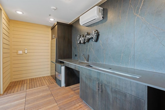 kitchen with an AC wall unit, sink, and light tile patterned floors