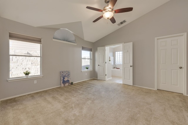 interior space featuring high vaulted ceiling, light colored carpet, ensuite bath, and ceiling fan