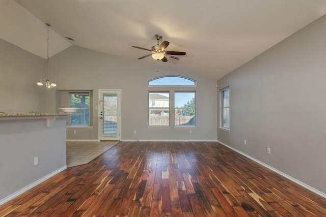 unfurnished living room with dark hardwood / wood-style flooring, high vaulted ceiling, and ceiling fan with notable chandelier