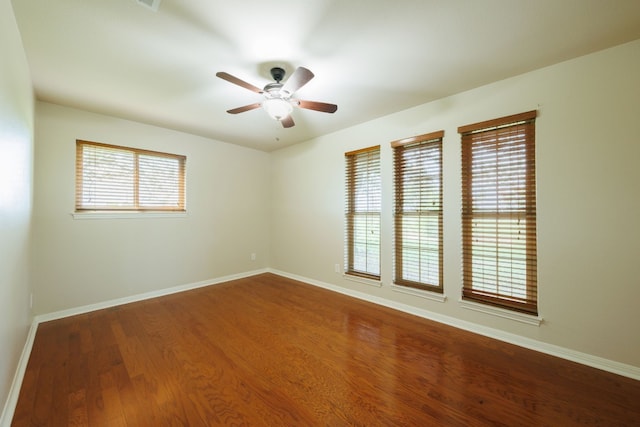 empty room with ceiling fan, dark hardwood / wood-style flooring, and a healthy amount of sunlight