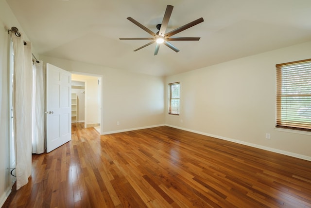 unfurnished bedroom featuring ceiling fan, wood-type flooring, and a spacious closet