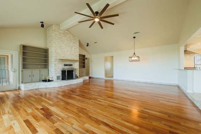 unfurnished living room with ceiling fan, beamed ceiling, high vaulted ceiling, a fireplace, and light wood-type flooring