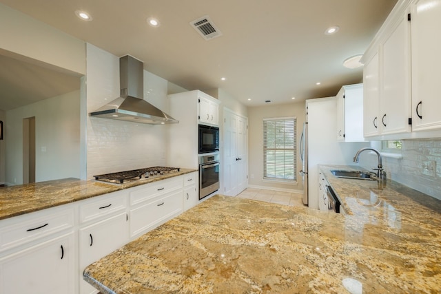 kitchen featuring white cabinetry, sink, wall chimney range hood, backsplash, and appliances with stainless steel finishes