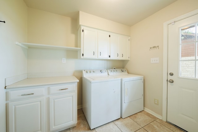 laundry area featuring washing machine and clothes dryer, light tile patterned floors, and cabinets