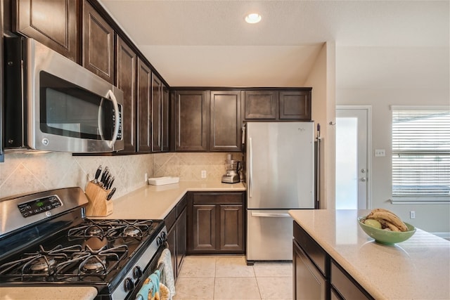 kitchen with decorative backsplash, dark brown cabinets, light tile patterned flooring, and stainless steel appliances