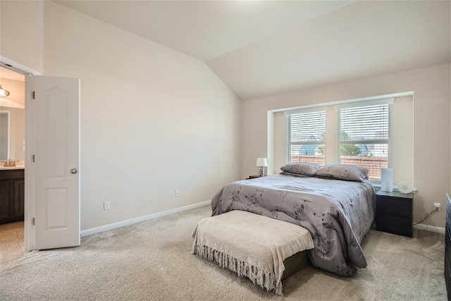 carpeted bedroom featuring vaulted ceiling, sink, and ensuite bath