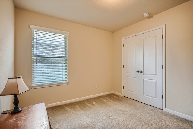 unfurnished bedroom featuring light carpet and a closet