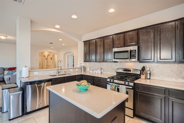 kitchen with dark brown cabinets, stainless steel appliances, sink, light tile patterned floors, and a center island