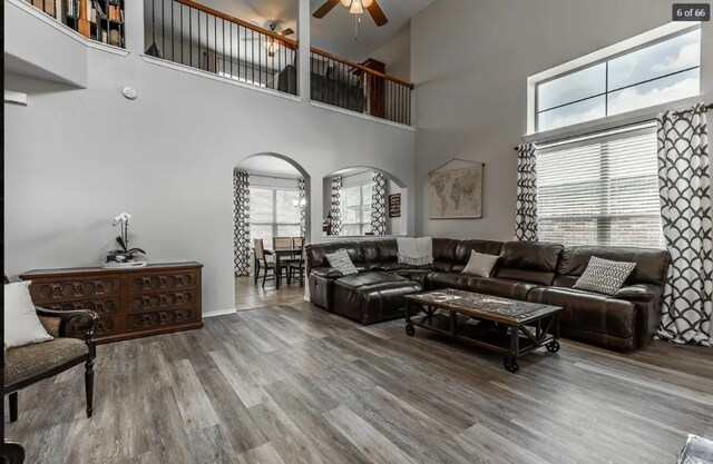 living room featuring ceiling fan, hardwood / wood-style flooring, and a towering ceiling