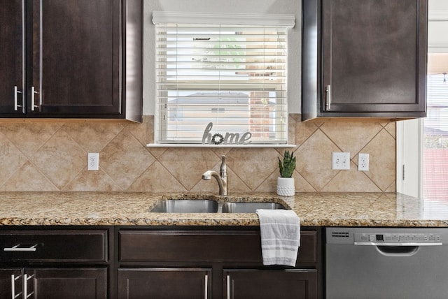 kitchen with dark brown cabinets, stainless steel dishwasher, sink, tasteful backsplash, and light stone counters