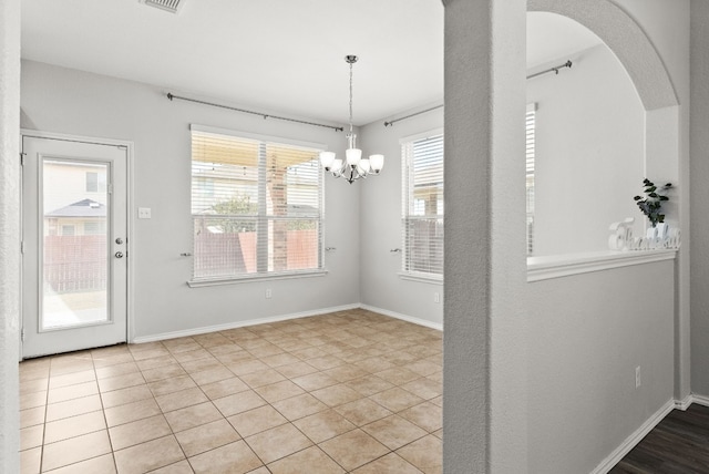 unfurnished dining area featuring an inviting chandelier and light tile patterned floors