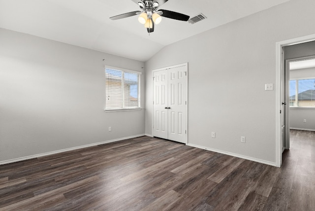 unfurnished bedroom featuring ceiling fan, multiple windows, dark hardwood / wood-style floors, and vaulted ceiling